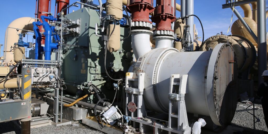 A large piece of rotating equipment outside under a blue sky.